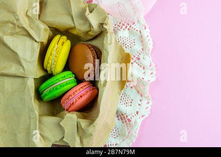 Yellow, pink, green and brown macaroons in the craft pack on pinc background Stock Photo