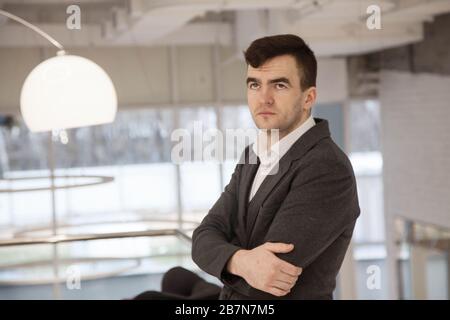 young businessman in a loose suit works in a light office Stock Photo