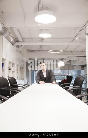young businessman in a loose suit works in a light office Stock Photo