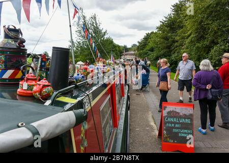 People looking at narrowboats moored along the canal towpath during summer waterways events in the UK. Stock Photo