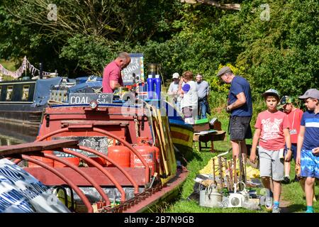 People looking at narrowboats moored along the canal towpath during summer waterways events in the UK. Stock Photo