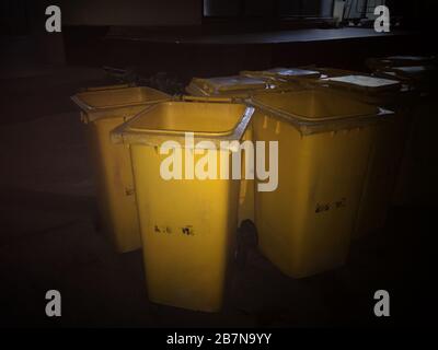 Garbage bin Yellow plastic bin trash at night time Stock Photo