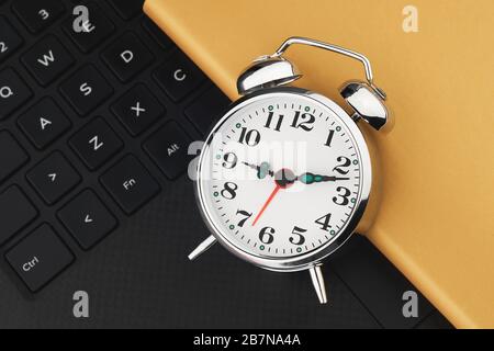 Metal vintage alarm clock on black keyboard. Laptop work and planning flat lay concept Stock Photo