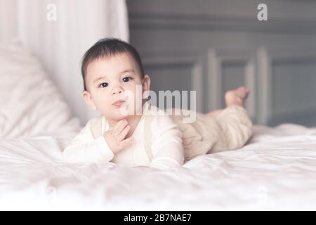 Funny baby boy under 1 year old wearing stylish pajamas lying in