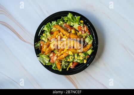 Take Away Healthy Cajun Salad with Chicken Fingers and Mustard Sauce in Black Plastic Plate Box / Package. Organic Fast Food. Stock Photo