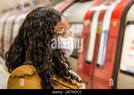 London, UK. 17th Mar 2020. A young black woman travels south - Anti Coronavirus (Covid 19) defences, wearing inefectual masks on the Northern Line of London Underground. Credit: Guy Bell/Alamy Live News Stock Photo