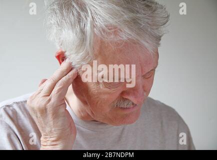 Older man with a hand to his ear has a possible infection Stock Photo