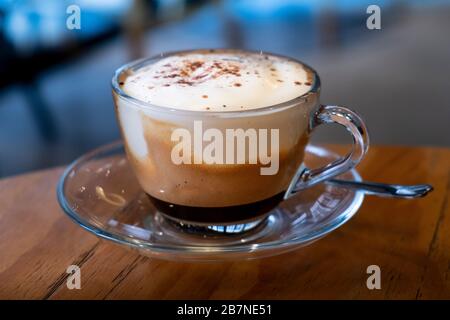 A cup of creamy coffee on a table in a restaurant Stock Photo