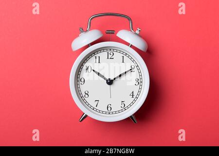 White vintage alarm clock on red background. Time concept Stock Photo
