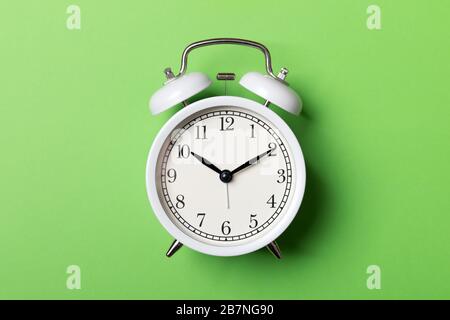 White vintage alarm clock on green background. Time concept Stock Photo