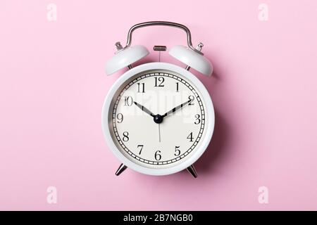 White vintage alarm clock on pink background. Time concept Stock Photo