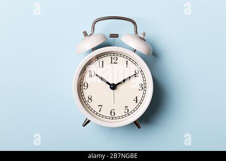 White vintage alarm clock on blue background. Time concept Stock Photo