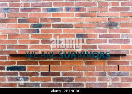 Johannesburg, South Africa - May 25, 2019: We are Survivors sign on brick wall in Apartheid Museum. Stock Photo