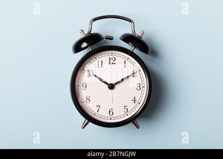 Black vintage alarm clock on blue background. Time concept Stock Photo