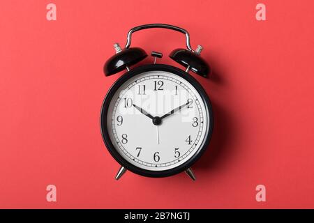 Black vintage alarm clock on red background. Time concept Stock Photo