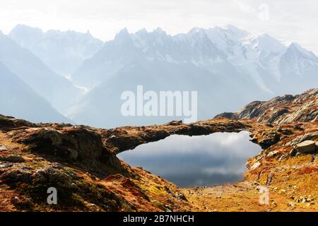 Colourful autumn landscape with Chesery lake (Lac De Cheserys) and snowy Monte Bianco mountains range on background. Vallon de Berard Nature Preserve, Chamonix, France Alps Stock Photo