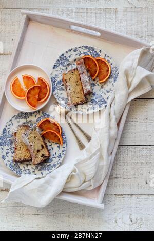 Sliced banana cake served with blood oranges on a white tray. Shot from above Stock Photo