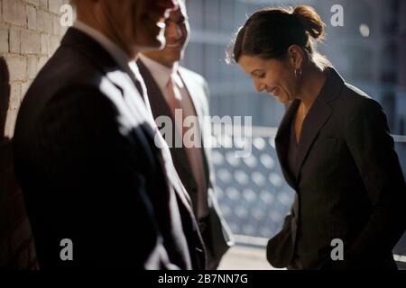 Smiling mid-adult businesswoman standing with two male colleagues. Stock Photo