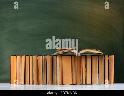 Back to school, pile of books with empty green school board background, education concept Stock Photo