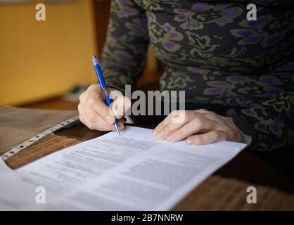 woman signs a contract at home Stock Photo