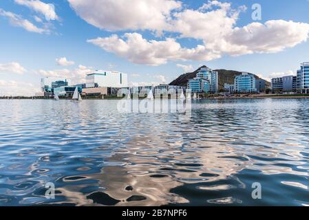 Tempe Town Lake south shore luxury waterfront condominiums and glass office buildings, blue skies and water, and a sail boats arriving from a regatta. Stock Photo