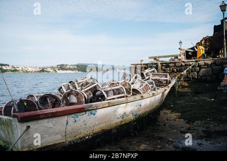 Fishing boat on ground because of low tide in Galicia, Northern Spain on a sunny day Stock Photo