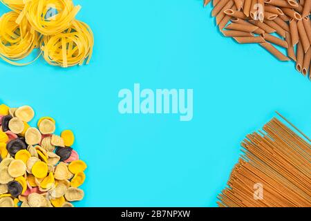 Different kinds of dry uncooked italian pasta on bright blue background, top view with copy space Stock Photo