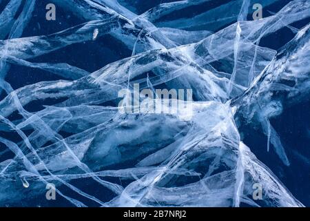 Beautiful patterns of cracks in blue transparent ice. The natural texture of ice. Horizontal. Stock Photo