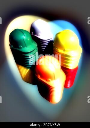 A pile of colorful hardhats with in a spotlight.  Safety concept. Stock Photo