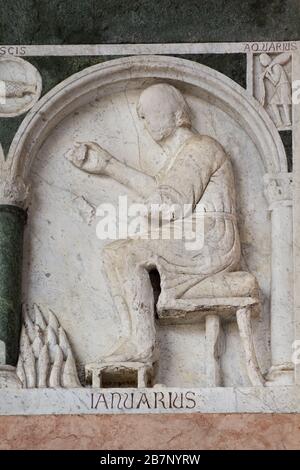 Sitting by the fire (January) - Labours of the Months (AD 1233) - Portico - Saint Martin’s Cathedral - Lucca, Italy Stock Photo