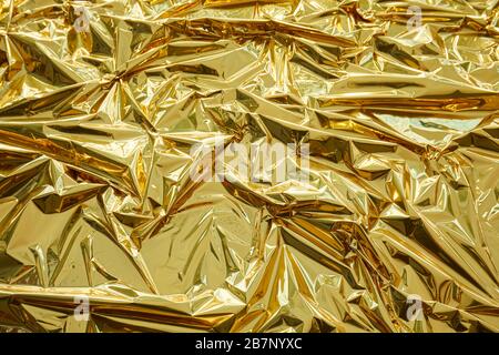 Crumpled, golden metallic foil texture background Stock Photo