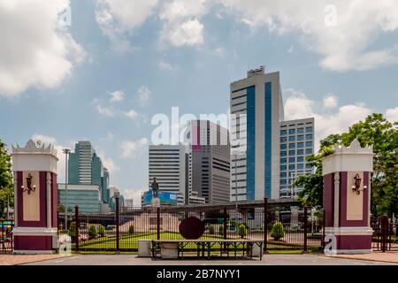 One of the entrances to Lumphini Park in Bangkok, Thailand, with the monument to King Rama VI and the skyscrapers of Silom in the background Stock Photo