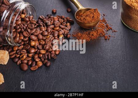 Roasted coffee beans and ground coffee on black table close-up Stock Photo