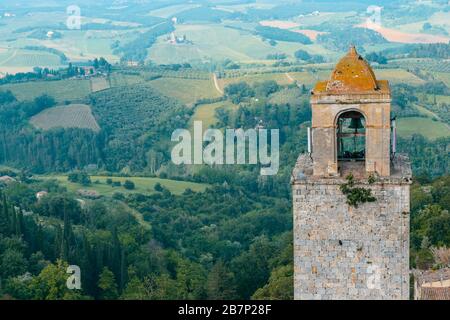 The top of Torre Rognosa with typical Tuscan countryside in the background seen from the top of the Great Tower (Torre Grossa), San Gimignano, Italy. Stock Photo
