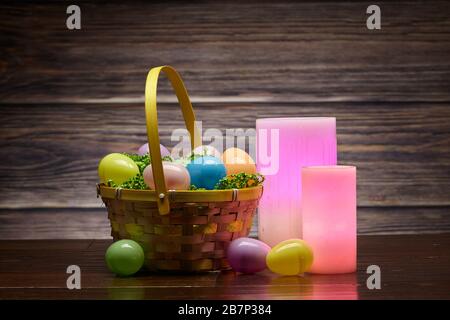 Basket of Easter Eggs and Glowing Wax Colored Candles Stock Photo