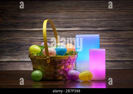 Basket of Easter Eggs and Glowing Wax Colored Candles Stock Photo