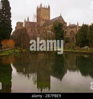 a springtime view of Wells Cathedral with its reflection in the ponds as seen from within the grounds of the Bishops Palace. Somerset England, UK Stock Photo