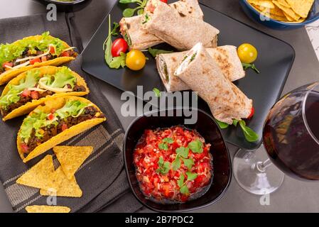 Various mixed Mexican dishes. Tacos, burritos, fajita, salsa, nachos on a dark table. View from above Stock Photo
