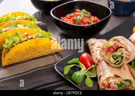 Various mixed Mexican dishes. Tacos, burritos, fajita, salsa on a dark table Stock Photo