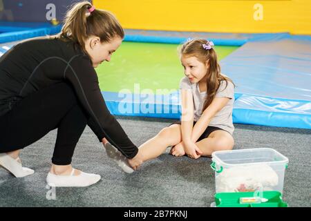 girl having pain in ankle and getting help after jumping on trampoline Stock Photo