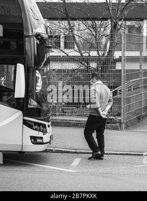 Kehl, Germany - Mar 16, 2020: anxious concerned driver of intercity bus wearing white protection mask checkpoint at border crossing crisis measures against coronavirus Stock Photo