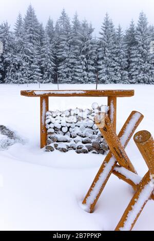 Stacked chopped firewood covered by snow in winter. Stacked wood covered with a snow. Woodshed outside in winter. Stock Photo