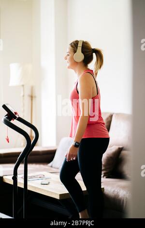 beautiful blonde caucasian athlete woman doing exercises with elastic band in living room at home Stock Photo