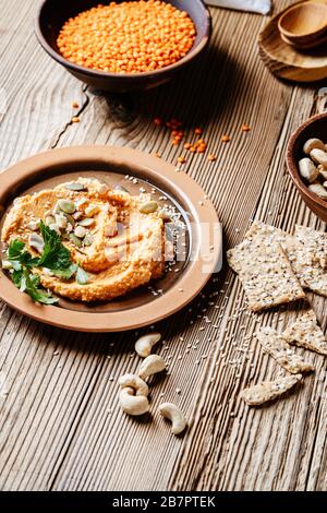 Healthy snack, gourmet dip. Lentil hummus with cashews, sesame seeds and sunflower seeds on rustic wooden table Stock Photo