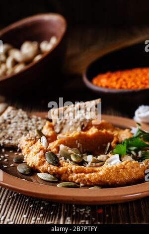 Healthy snack, gourmet dip. Lentil hummus with cashews, sesame seeds and sunflower seeds on rustic wooden table Stock Photo