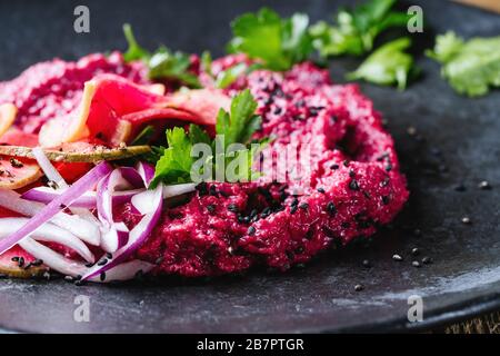 Beetroot horseradish  hummus with pickled watermelon radishes on rustic wooden table, plant based food, close up Stock Photo