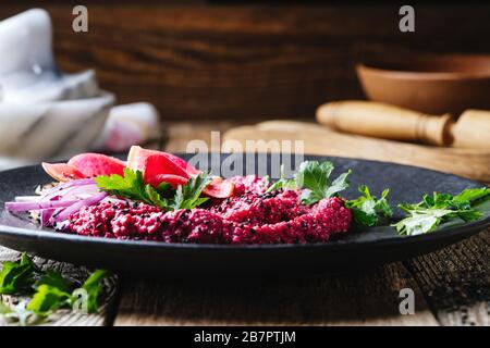 Beetroot horseradish  hummus with pickled watermelon radishes on rustic wooden table, plant based food, close up Stock Photo