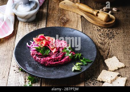Beetroot horseradish  hummus with pickled watermelon radishes on rustic wooden table, plant based food, close up Stock Photo