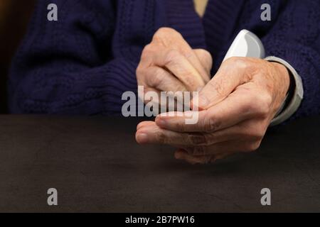 Close up picture of elderly female hands taking medication, dark backgrund Stock Photo