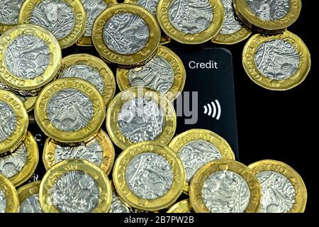 CARDIFF, WALES - JANUARY 2020: Close up view of British currency GBP - One Pound coins on top of a credit card with a contactless payment symbol Stock Photo